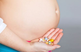 una pancia incinta e una mano con in mano delle pillole